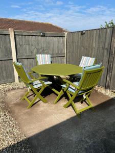 een groene picknicktafel en twee stoelen naast een hek bij SUNNY RHYL BUNGALOW in Rhyl