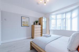 a white bedroom with a bed and a dresser at "Eastville Court Rhyl" by Greenstay Serviced Accommodation - Cosy 2 Bedroom Bungalow with Parking, Netflix & Wi-Fi, Close To Beaches, Shops & Restaurants - Ideal for Families, Business Travellers & Contractors in Rhyl