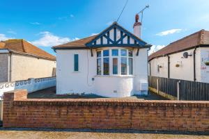 a white and black house with a brick wall at "Eastville Court Rhyl" by Greenstay Serviced Accommodation - Cosy 2 Bedroom Bungalow with Parking, Netflix & Wi-Fi, Close To Beaches, Shops & Restaurants - Ideal for Families, Business Travellers & Contractors in Rhyl
