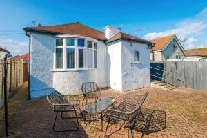 a patio with chairs and a table in front of a house at "Eastville Court Rhyl" by Greenstay Serviced Accommodation - Cosy 2 Bedroom Bungalow with Parking, Netflix & Wi-Fi, Close To Beaches, Shops & Restaurants - Ideal for Families, Business Travellers & Contractors in Rhyl
