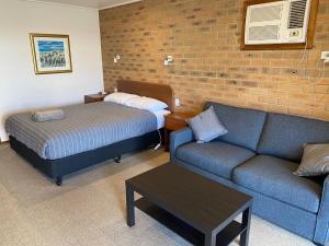 ein Wohnzimmer mit einem Sofa und einem Bett in der Unterkunft Quays Motel San Remo in San Remo