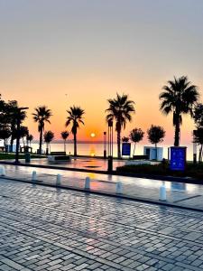 a sunset in a park with palm trees and the ocean at CAMP&HOSTEL Antalya in Antalya