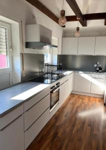 a kitchen with white cabinets and a wooden floor at 110 qm Stadtnahe Oase im Grünen in Priesendorf