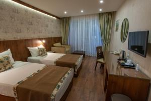 una camera d'albergo con due letti e una televisione di Family Hotel Berlin Beach Sveti Vlas a Sveti Vlas Altre 58 foto