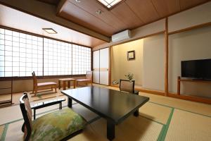 a living room with a table and chairs and a tv at Osakaya Ryokan in Kusatsu