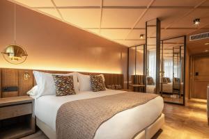 een slaapkamer met een groot wit bed en een spiegel bij Room Mate Leo in Granada