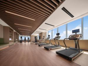 a gym with a row of treadmills and windows at Holiday Inn Shijiazhuang High-tech Zone, an IHG Hotel in Shijiazhuang