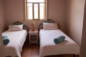 two twin beds in a room with a window at Kleingeluk Guest Farm in De Rust +50 photos