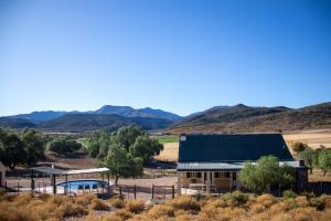 a house in the desert with mountains in the background at Kleingeluk Guest Farm in De Rust