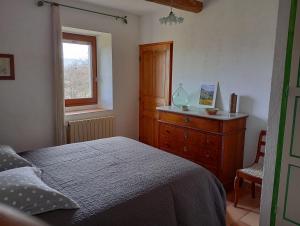 a bedroom with a bed and a dresser and a window at Le Lavoir in Lacoste
