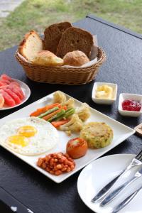 een tafel met een bord ontbijtproducten en een broodmand bij Meraki Holistic Wellness Retreat in Burhānilkantha