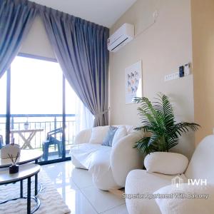uma sala de estar com um sofá branco e uma planta em Ipoh Horizon Skypool Town Suites 4-11pax by IWH Suites em Ipoh