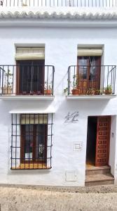 een wit gebouw met twee ramen en een deur bij La Casa de Abuela in Frigiliana