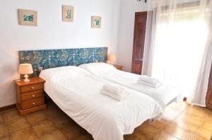 two beds in a bedroom with white sheets and towels at La Casa de Abuela in Frigiliana