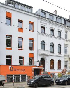 pomarańczowo-biały budynek z samochodami zaparkowanymi przed budynkiem w obiekcie Townside Hostel Bremen w Bremie