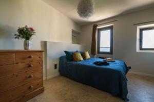 a bedroom with a bed and a dresser and windows at Maison de village Luberon in Lauris