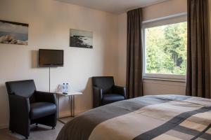 a bedroom with two chairs and a bed and a window at Landhaus Eifelsicht in Hellenthal