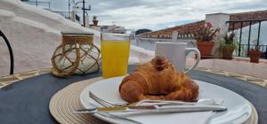 a table with a plate of food and a glass of orange juice at LA CASA DE ABUELA Habitaciones con baño compartido en el casco histórico de Frigiliana "sólo adultos" in Frigiliana