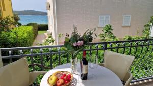 a table with a vase of flowers and a bowl of fruit at Apartments Mediteraneo in Zaboric