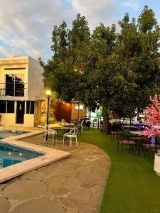 a patio with tables and chairs and a tree at VILLA NAPOLI in Santa Ana