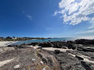 una playa con rocas y el océano en un día nublado en MH VAL&YVAN plage, piscine pointe de Trévignon et concarneau, en Trégunc