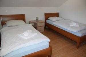 2 Betten mit weißer Bettwäsche und Handtüchern auf einem Zimmer in der Unterkunft Apartma narava in Begunje pri Cerknici