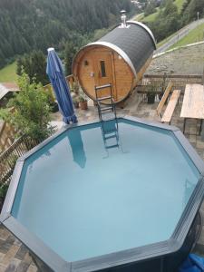 a swimming pool with a sauna and a house at Landhaus Oberzinnegg in Saalbach-Hinterglemm