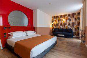 een slaapkamer met een groot bed en een blauwe bank bij DuoMo Hotel in Rimini