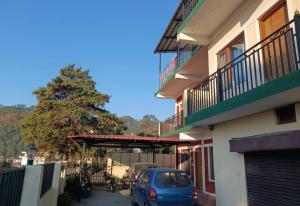 a blue car parked in a parking lot next to a building at Four Season Homestay Bhowali Bhimtal in Bhowāli