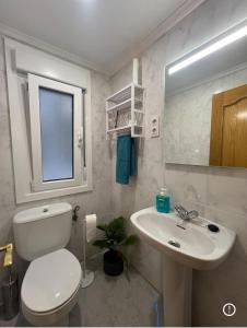 La salle de bains blanche est pourvue de toilettes et d'un lavabo. dans l'établissement Piso playa Gijon, à Gijón
