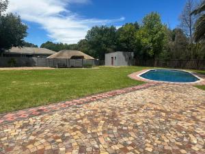 a brick walkway around a swimming pool in a yard at Starpoint Guest house in Vereeniging