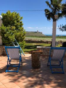 dwa niebieskie krzesła, stół i palma w obiekcie Tenuta L'Alba di monte Matino w mieście Otranto