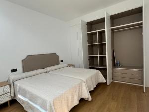 a white bedroom with a bed and a closet at Apartamentos Arcos de Montemar in Torremolinos