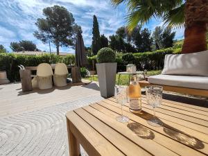 een houten tafel met twee glazen en een fles wijn bij Appartement 80 m2 avec jardin - 50m de la plage TIKI in Saint-Raphaël