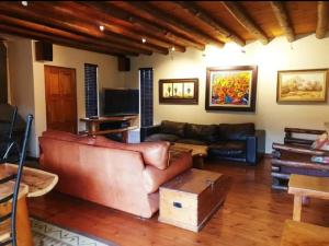a living room with a leather couch and a tv at Coming Home in Centurion
