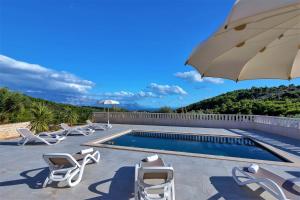 a pool with lounge chairs and an umbrella at Villa Lokanjac with pool and panoramic sea view in Selca