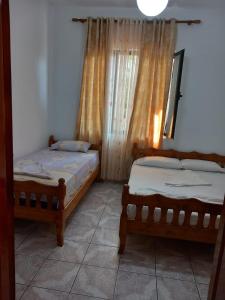 Dos camas individuales en una habitación con ventana. en Villa Kaja, en Durrës