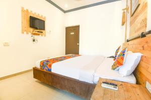 a bedroom with a bed and a tv on the wall at FabExpress Neo Calangute Beach Resort in Calangute