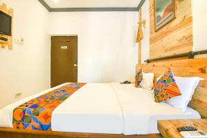 a bedroom with a large white bed with a wooden headboard at FabExpress Neo Calangute Beach Resort in Calangute
