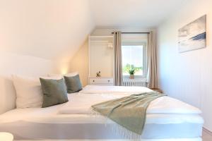 a bedroom with a large white bed with a window at Traumblick 4 mit Meerblick nach Amrum in Utersum