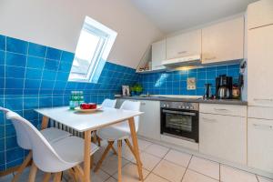 a kitchen with a white table and chairs and blue tiles at Traumblick 4 mit Meerblick nach Amrum in Utersum