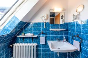 a blue tiled bathroom with a sink and a radiator at Traumblick 3 in Utersum