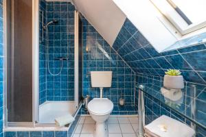 a blue tiled bathroom with a toilet and a shower at Traumblick 3 in Utersum