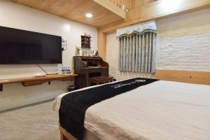 a bedroom with a large flat screen tv and a bed at Maizuru in Tainan