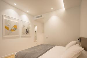 バレンシアにあるMon Suites Jardín de Ayoraの白いベッドルーム(ベッド1台付)が備わります。壁には絵画が飾られています。