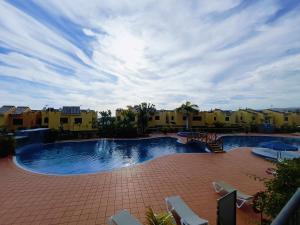 ein großer Pool mit Stühlen und Gebäuden in der Unterkunft Luxury House with sea view, hottub & pool in San Bartolomé de Tirajana + 21 Fotos