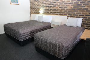 a hotel room with two beds and a brick wall at Top of the Town Motel in Inverell