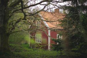 ein rotes Haus mit einem Baum davor in der Unterkunft Munkedals Herrgård in Munkedal