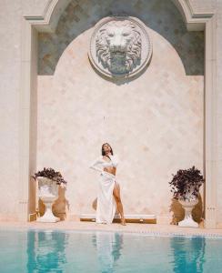 Eine Frau in einem weißen Kleid steht neben einem Pool in der Unterkunft Villa Le Premier Maestro in Odessa