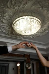 twee mensen die handen vasthouden onder een plafond licht bij Nota Bene Hotel & Restaurant in Lviv